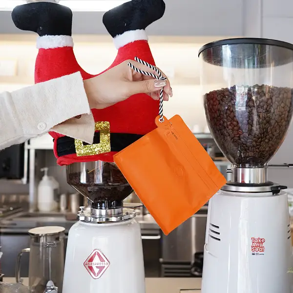 Sosteniendo de la mano bolsas de café de 150g con cordón en la cafetería
