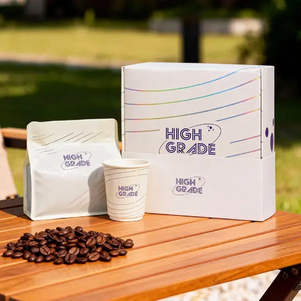 Caja de café personalizada de marca con bolsa de café a juego y vaso de papel expuesta al aire libre sobre una mesa de madera