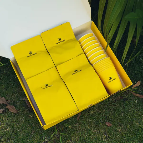 Vista interior de una caja de café de papel personalizada con bolsas y tazas de café ordenadas