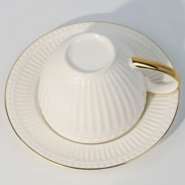 Vista inferior de una taza cerámica en relieve con platillo a juego