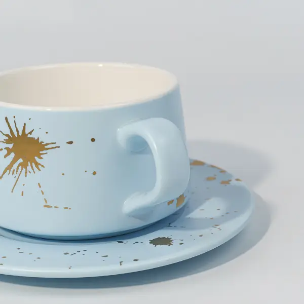 Detalle de mango de taza de café de cerámica con decoración con salpicaduras de pan de oro