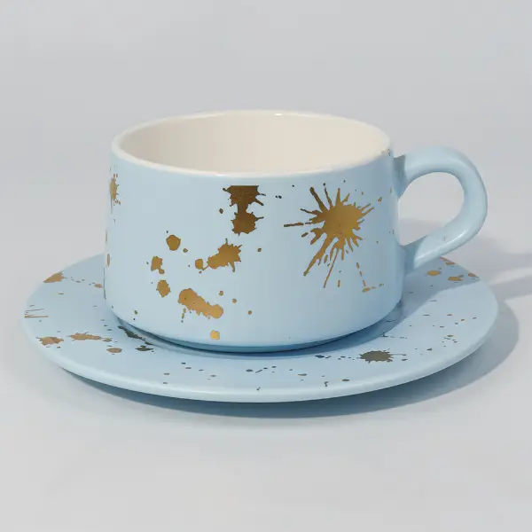 Vista lateral de una taza de café de cerámica de pan de oro con diseño de salpicaduras pintado a mano