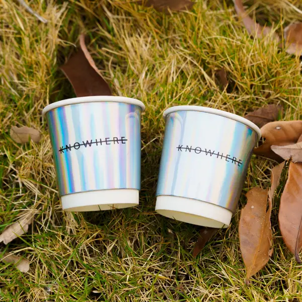 Vasos de papel holográficos con papel de aluminio arcoíris en la escena de estilo de vida al aire libre