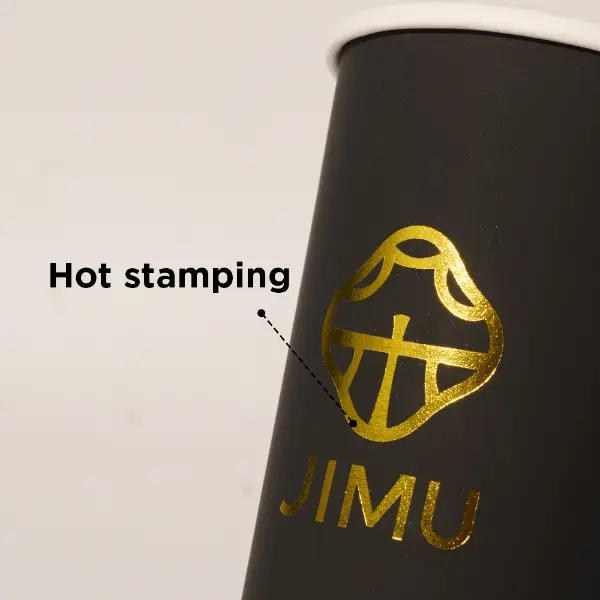 Detalle de estampado en caliente con papel de aluminio dorado en un vaso de papel negro premium