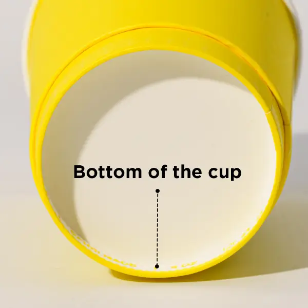 Primer plano de la estructura inferior de un vaso de papel amarillo que muestra el diseño de la base del vaso