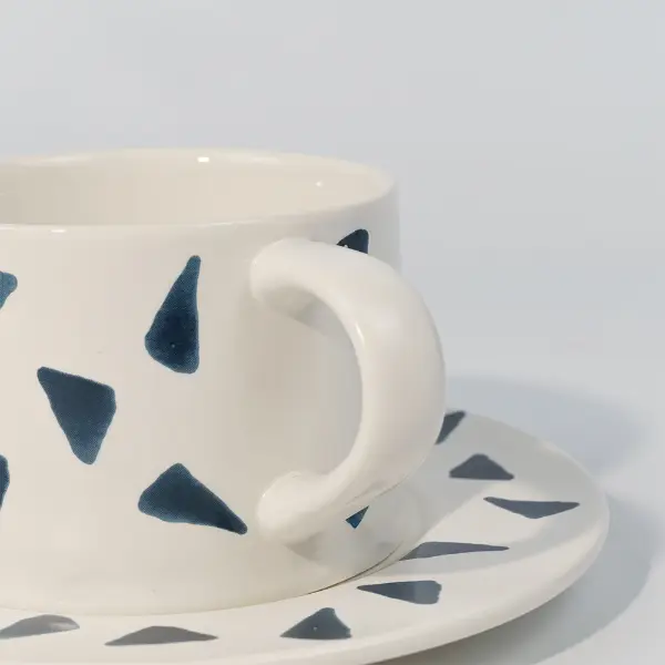 Primer plano del asa en una taza de café cerámica impresa con estampado decorativo